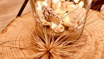 A glass container filled with seashells and a decorative plant on a wooden surface.