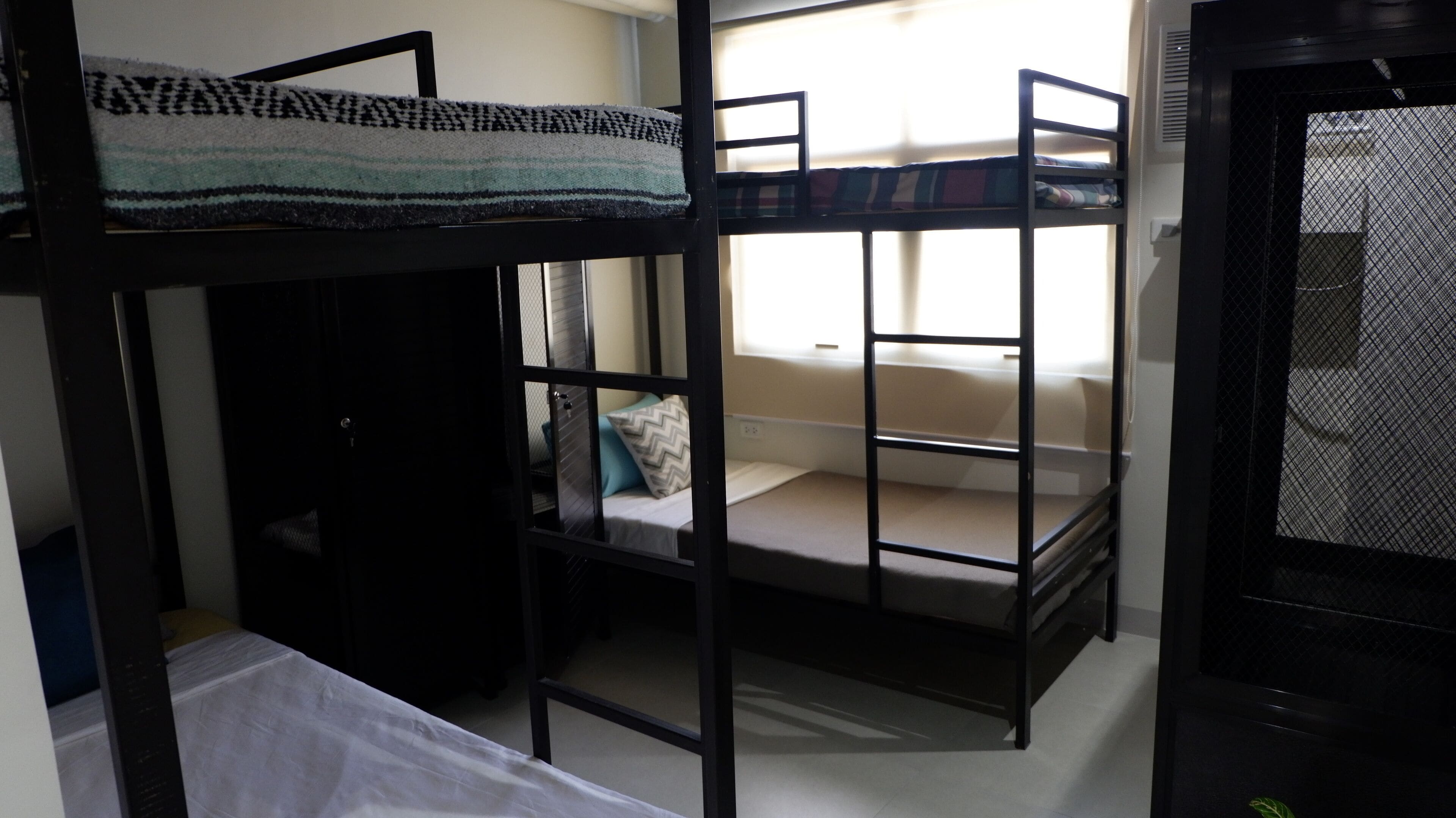 A bunk bed room with a window, a door, and a small table.