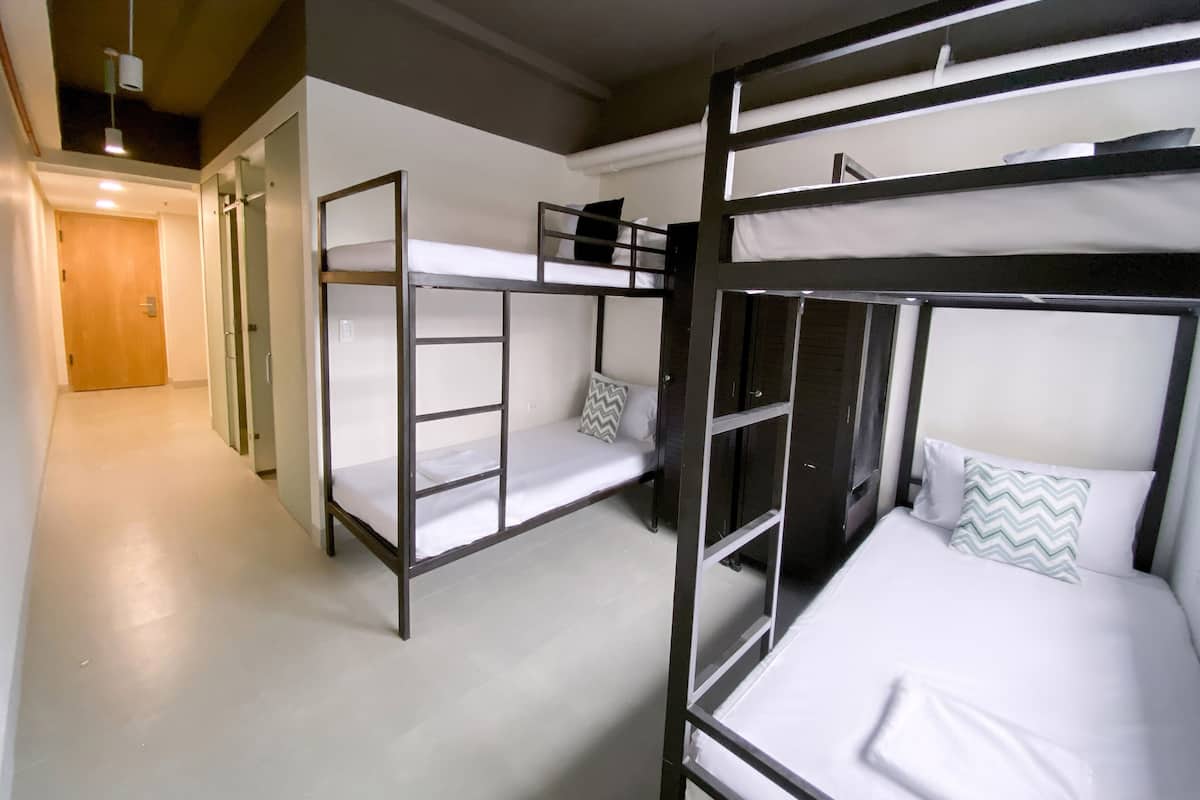 A dormitory room with bunk beds, a door, and a hallway.