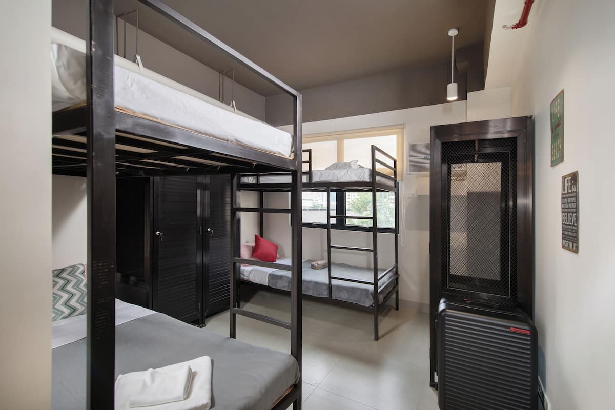 A dormitory room with bunk beds, a desk, and a window.