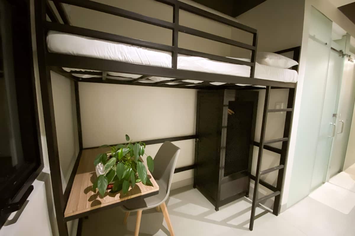 A bunk bed with a desk and chair, a potted plant, and a sliding door.
