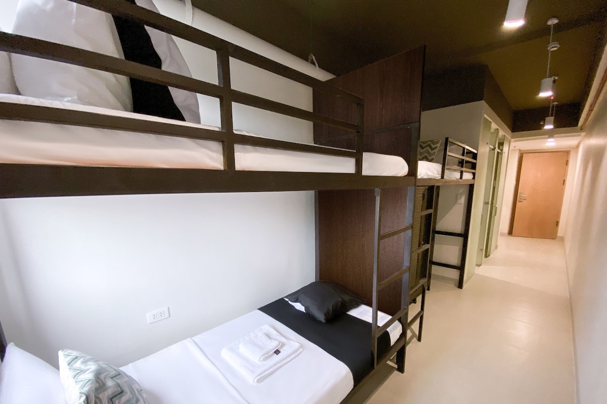 A bunk bed room with a ladder, a small table, and a pillow.