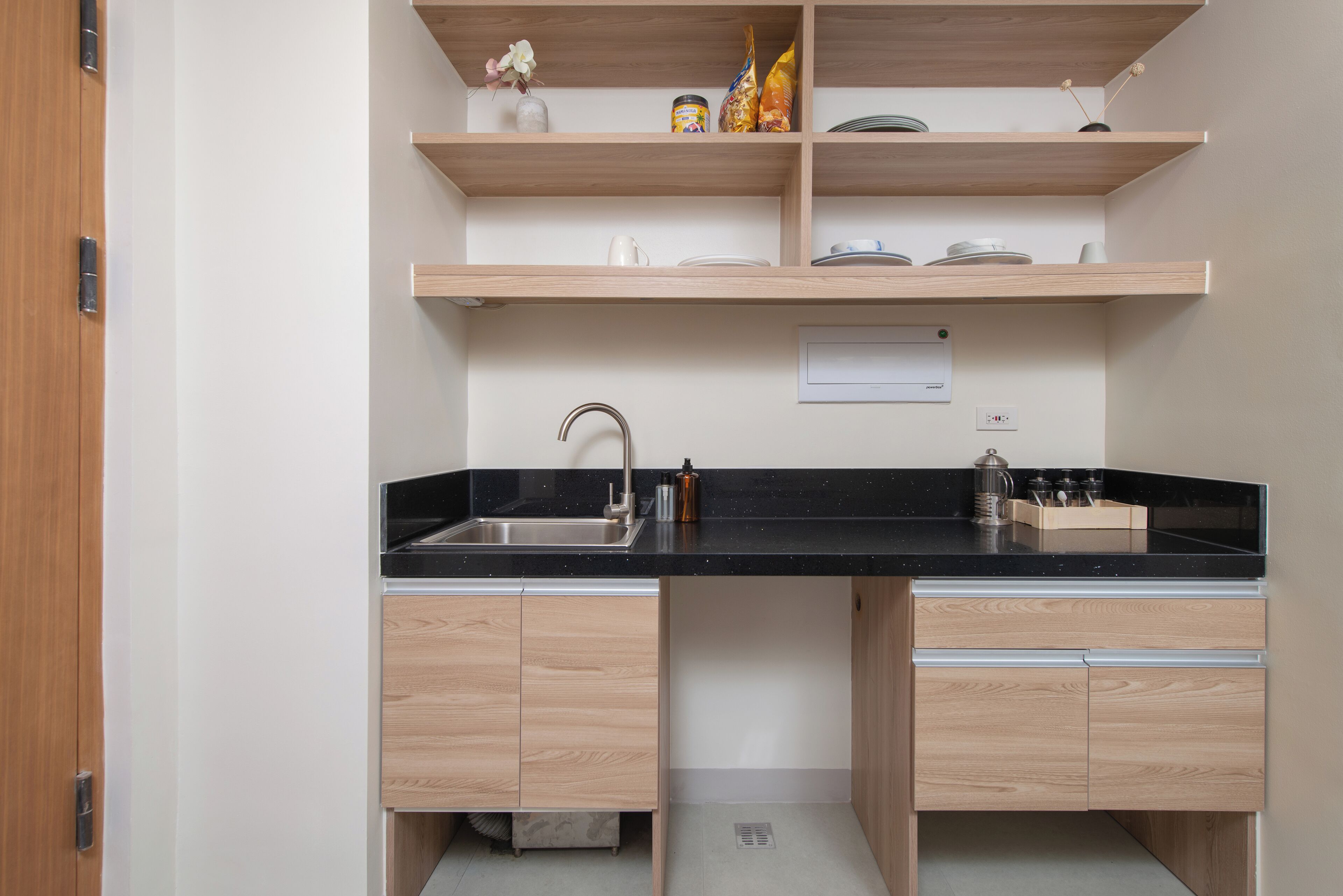 A kitchen with wooden cabinets, a black countertop, and a stainless steel sink.