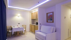 A modern living room with a white sofa, a dining table with chairs, and a kitchen area. - My Way Luxury Ibiza (Sant Josep de sa Talaia)