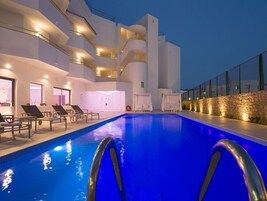 Un hotel moderno con piscina, sillones de descanso y un muro de piedra.