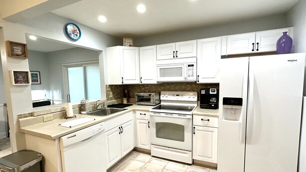 A modern kitchen with white cabinets, a built-in microwave, a stove, and a refrigerator. - Private Spacious 1BR Near LEGOLAND 2 Miles (Winter Haven)