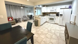 A modern kitchen with white cabinets, a microwave, a stove, and a refrigerator. There is a dining area with a table and chairs. - Private Spacious 1BR Near LEGOLAND 2 Miles (Winter Haven)