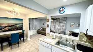 A modern kitchen with white cabinets, a stainless steel sink, and a dining area with a table and chairs. - Private Spacious 1BR Near LEGOLAND 2 Miles (Winter Haven)