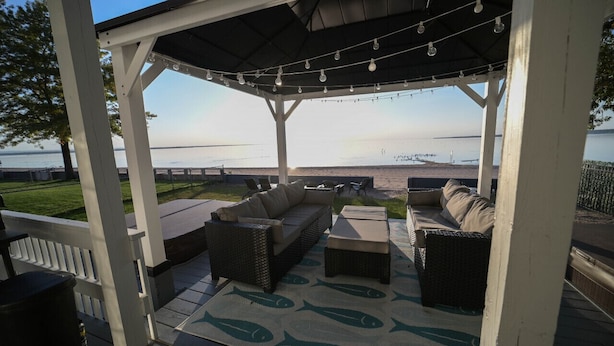 A covered outdoor seating area with wicker furniture and a view of the water.