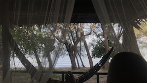 A hammock under a canopy overlooking a lake with trees. - Naks Shack (Prey Nob)