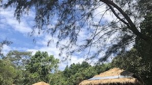 Two thatched-roof huts with solar panels, surrounded by dense trees and a clear sky. - Naks Shack (Prey Nob)