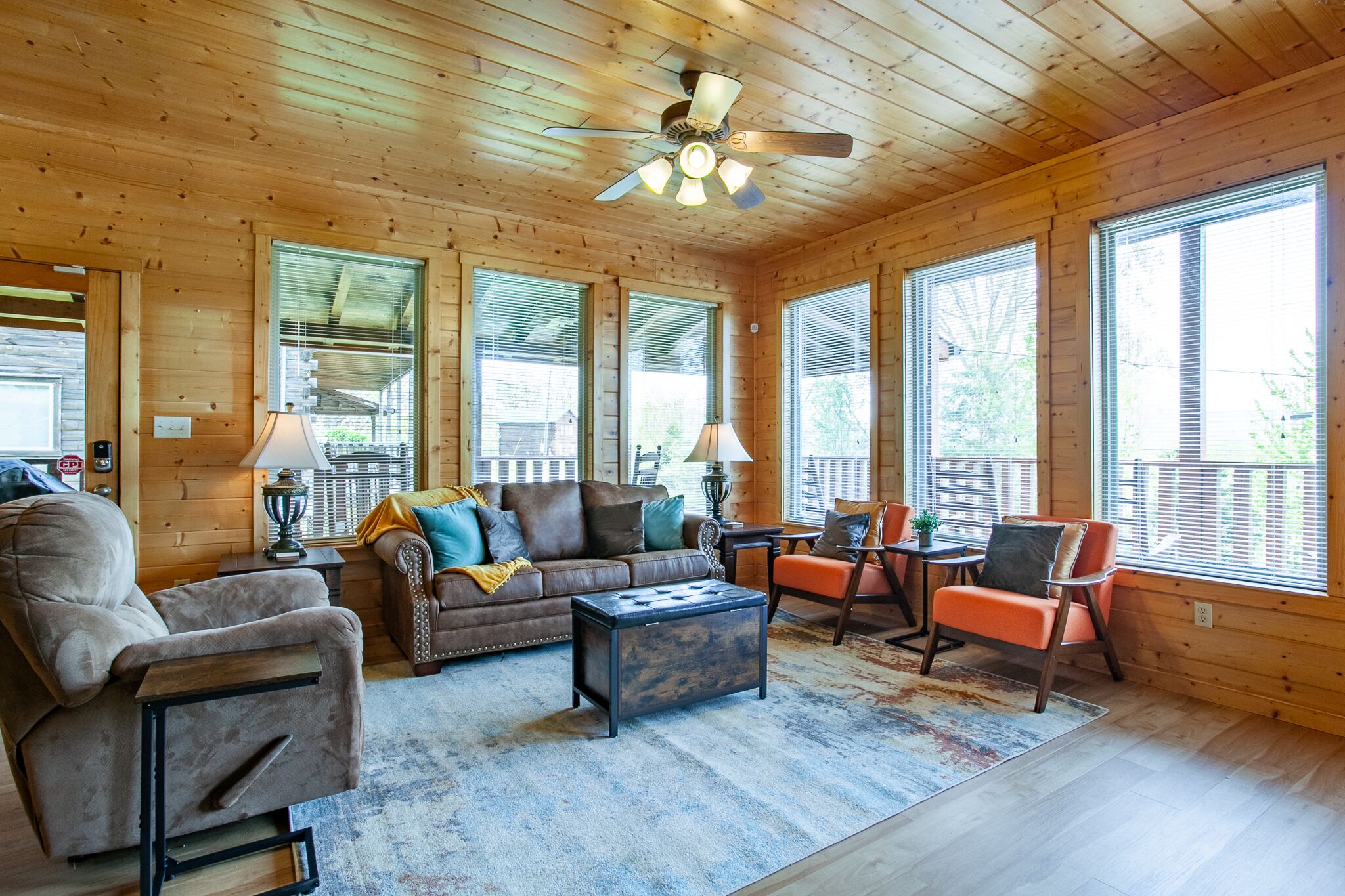 A cozy log cabin interior with a sofa, armchair, ottoman, and a small table.