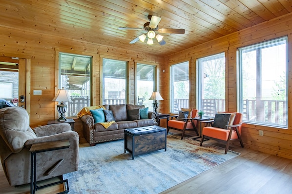 A cozy log cabin interior with a sofa, armchair, ottoman, and a small table. - Cozy Mountain Cabin I A++ Views & Amenities (Sevierville)