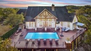 A large house with a swimming pool, deck, and outdoor furniture. - Sleeps 20 | Pool, Game Room | Luxury Fall Retreat (Dripping Springs)