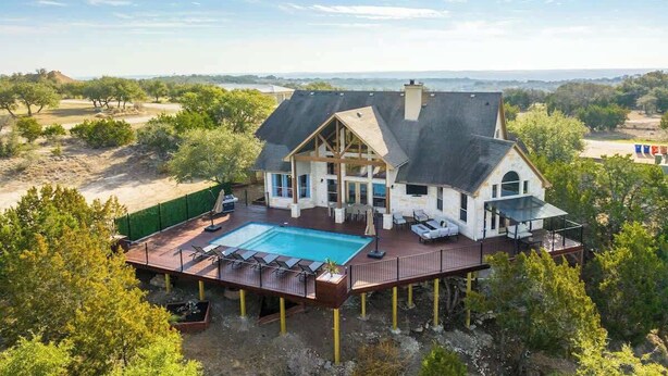 A large house with a swimming pool, deck, and multiple rooms. - Sleeps 20 | Pool, Game Room | Luxury Fall Retreat (Dripping Springs)