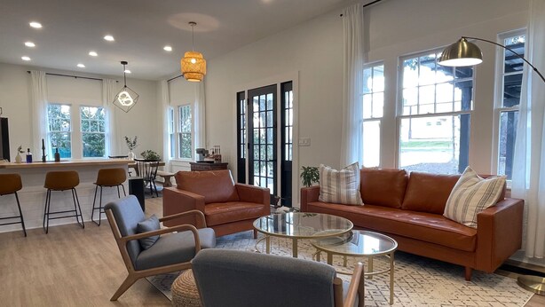 A modern living room with a sofa, chairs, a coffee table, and a dining area with a bar.