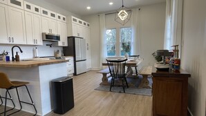 A modern kitchen with white cabinets, a central island, and a dining area with a wooden table and chairs.