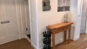 Um corredor com um aparador de madeira, um relógio fixado na parede e um quadro emoldurado.