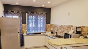 Eine moderne Küche mit Kühlschrank, Herd, Spüle und einem Fenster mit gemusterten Vorhängen.