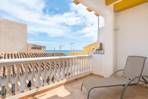 A balcony with a chair, a tiled floor, and a view of the sea.