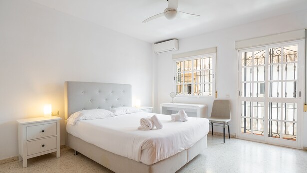 A neatly arranged bedroom with a bed, bedside tables, a chair, and a window with a view.