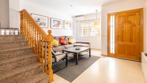 A living room with a staircase, a sofa, a coffee table, and a wooden door.