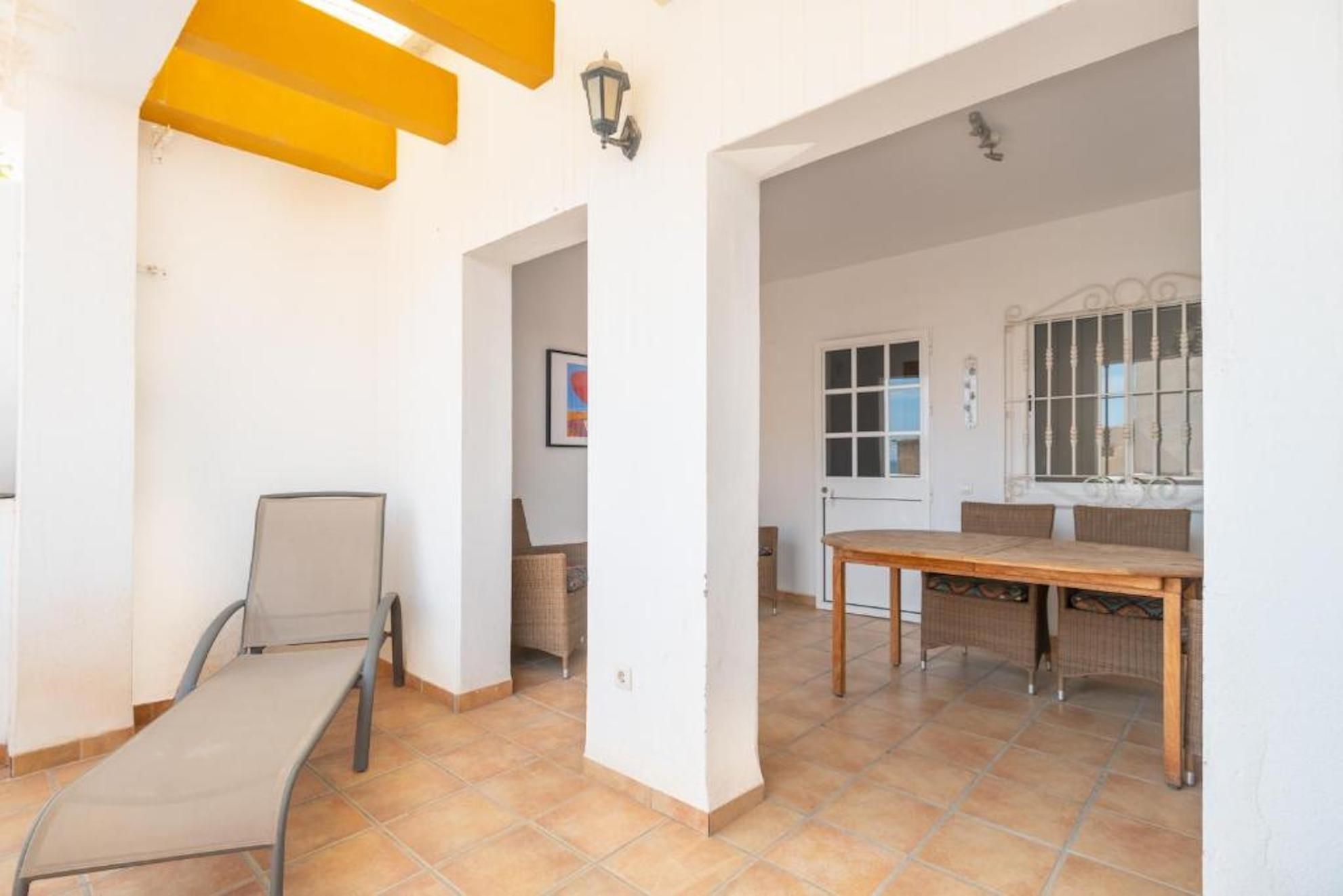 Una habitación con una mesa de comedor, sillas, un banco e iluminación de pared.