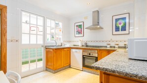 A kitchen with wooden cabinets, a dishwasher, an oven, granite countertops, and a window with a view.