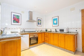 A kitchen with wooden cabinets, a built-in oven, a microwave, and a sink. - RENTS Victoria Beach (La Cala Del Moral Rincon de la Victoria)