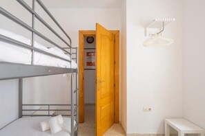 A bunk bed room with a wooden door and a small table. - RENTS Victoria Beach (La Cala Del Moral Rincon de la Victoria)