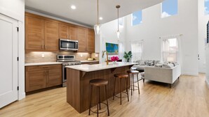 Une cuisine moderne avec des meubles en bois, des appareils électroménagers en acier inoxydable et un îlot central doté de tabourets.