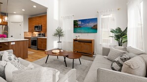 Un espace de vie moderne comprenant une cuisine, un téléviseur à écran plat et un coin salon confortable.