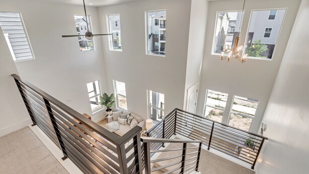 Un intérieur spacieux avec un plafond haut, de nombreuses fenêtres et un escalier moderne doté de rampes en métal.