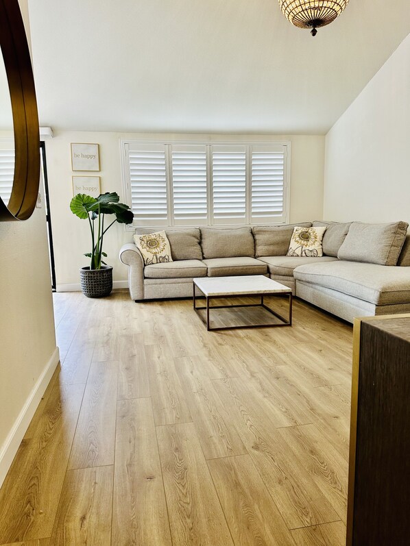 A living room with a sectional sofa, a coffee table, and a potted plant.