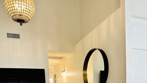 Una sala de estar moderna con una mesa de centro de mármol, un espejo redondo grande y un mueble de madera oscura.