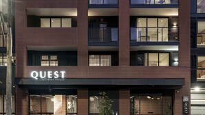 Ein modernes Gebäude mit der Aufschrift "QUEST APARTMENT HOTELS", das ein Hotel kennzeichnet.