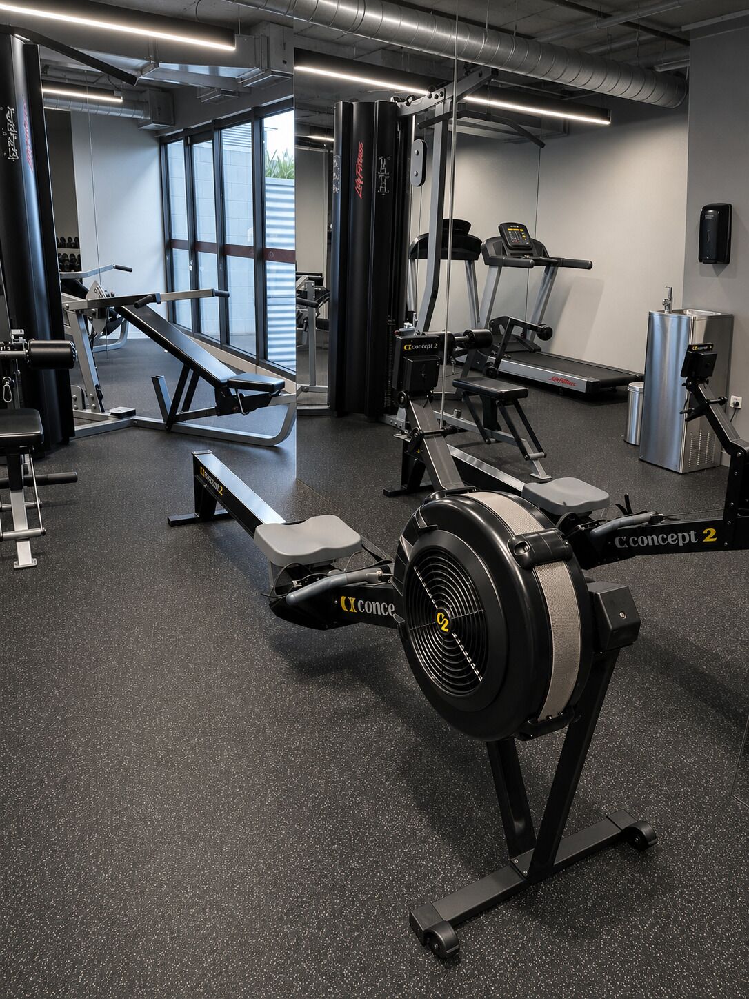 Ett gym med konditionsmaskiner, utrustning för styrketräning och en träningsbänk.
