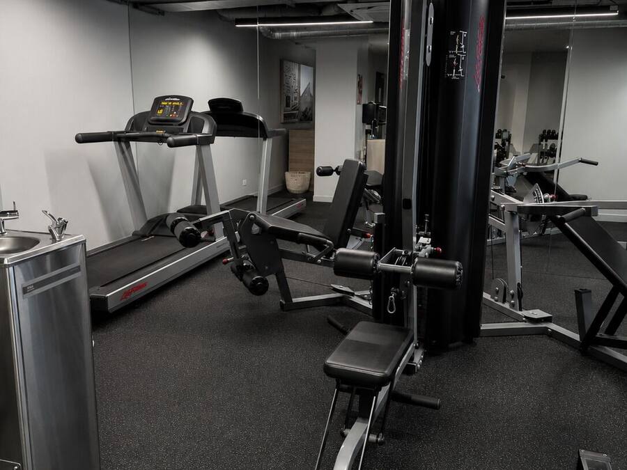 A gym with exercise equipment, a treadmill, and a mirrored wall.