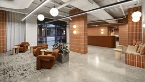 Eine moderne Lobby mit Sitzbereichen, einem Empfangstresen und einem großen Fenster.