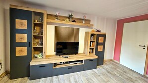 Un mueble moderno para entretenimiento con televisor de pantalla plana, repisas integradas y acabado de madera.