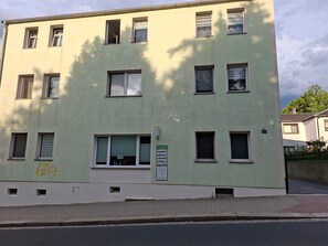 Un immeuble à plusieurs étages doté d’une façade plane, de nombreuses fenêtres et d’une entrée au niveau du sol avec une porte.