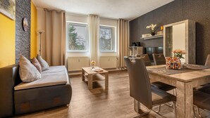Ein modernes Wohnzimmer mit einer Couch, einem Esstisch, Stühlen und einem großen Spiegel.