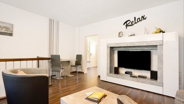 Ein modernes Wohnzimmer mit Kamin, einem Flachbildfernseher und einem Schild mit der Aufschrift 'Relax'.