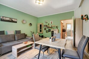 Un salon moderne avec un canapé, une table à manger et un coin cuisine visible à travers une porte ouverte.
