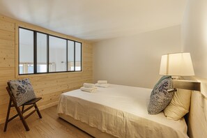 Enjoy a peaceful retreat with a large window offering a view of the outdoors, a comfortable bed, and a cozy chair.
