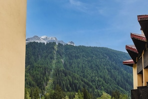 A mountain landscape with a forested hill and a building with a red roof.