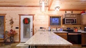 Una cocina con paredes de madera, encimera de granito y electrodomésticos de acero inoxidable.