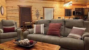 Interior acogedor de una cabaña de troncos, con un conjunto de sofás, una mesa de centro de madera y un comedor.