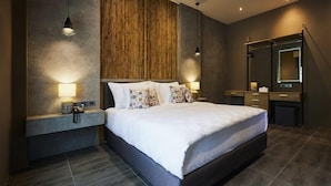 A modern bedroom with a large bed, bedside lamps, a wooden accent wall, and a built-in wardrobe. - Sand Dollar Boutique Hotel (Sattahip)