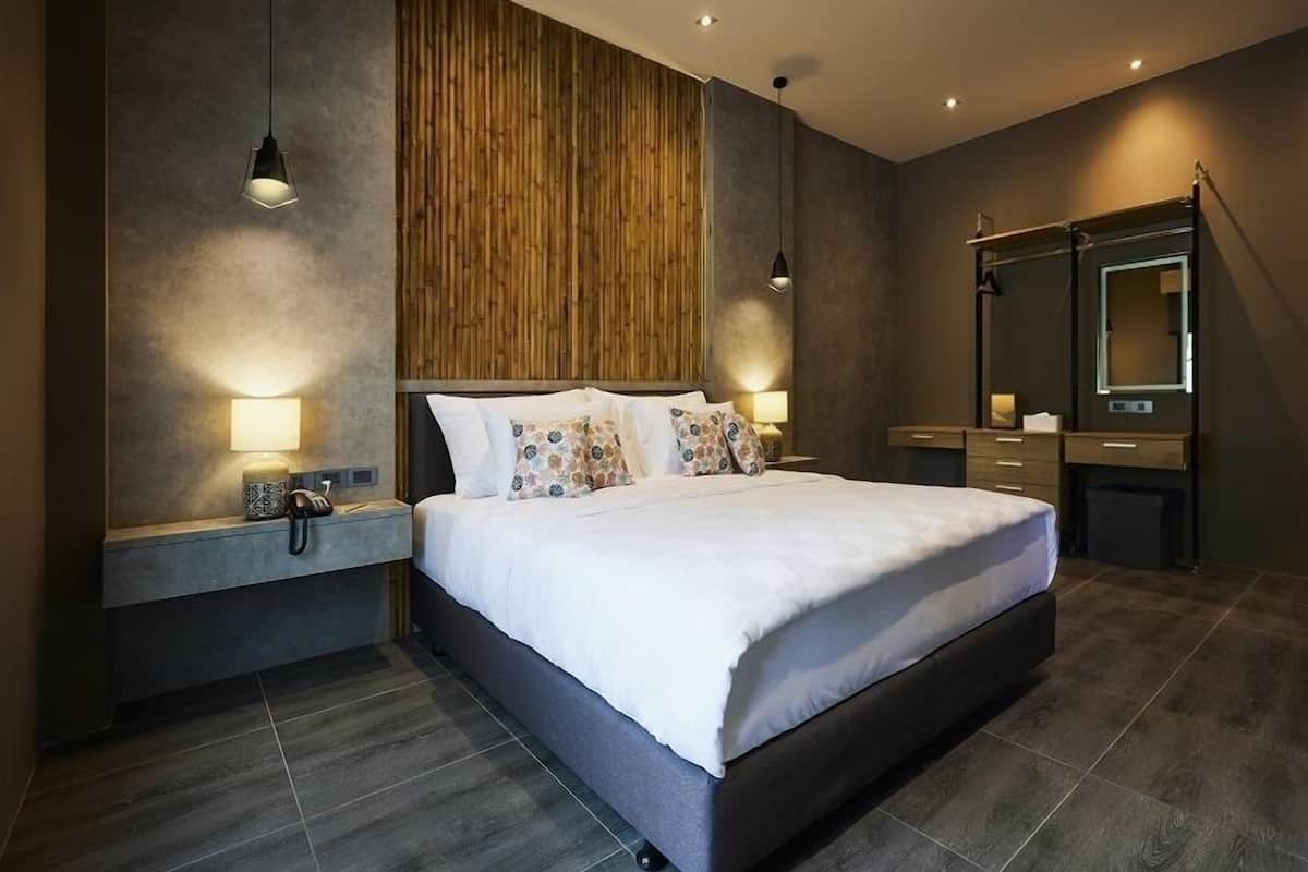 A modern bedroom with a large bed, bedside lamps, a wooden accent wall, and a built-in wardrobe.